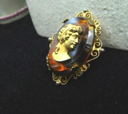 2" OVAL GOLD CAMEO LADY TO THE RIGHT ON AMBER GLASS FRAME BROOCH